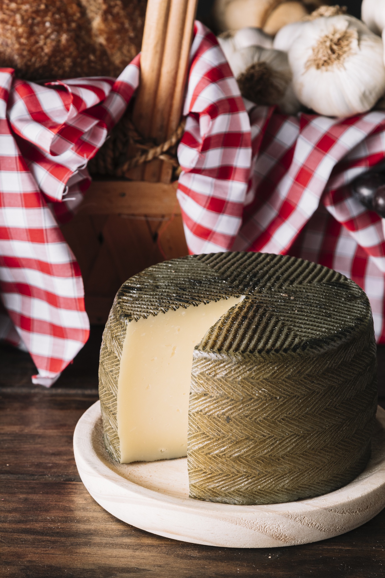 Queijo artesanal com ervas ao lado de uma cesta de piquenique